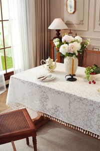 Detailed close-up of French lace tablecloth featuring elegant vine patterns and tassel fringe