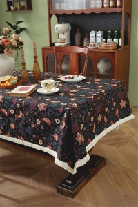 Macro shot of retro dark blue floral tablecloth featuring white tassel fringe edge