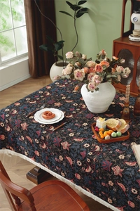 Detailed close-up of vintage floral jacquard tablecloth with elegant white cotton tassels