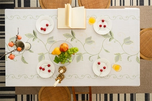 Close-up of rectangle tablecloth featuring green leaf embroidery and scalloped edges