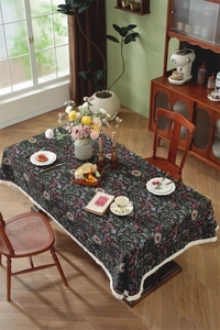 Detail of vintage floral tablecloth featuring beige tassels and dense cotton-linen texture