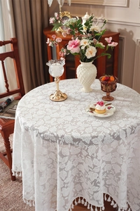 Close-up of white lace tablecloth with leaf patterns and delicate fringe tassels