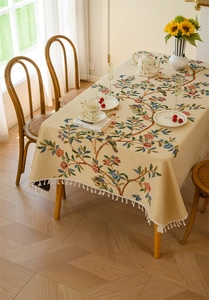 Detail of floral jacquard tablecloth featuring vintage bird patterns and fringe tassels
