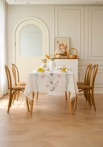 Close-up of floral embroidery on cream waterproof tablecloth with fringe edge details