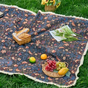 Detailed close-up of thickened woven picnic blanket with vintage floral bird patterns and tassels