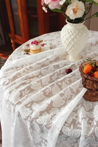 Detail of white lace tablecloth showing intricate leaf patterns and elegant floral mesh texture