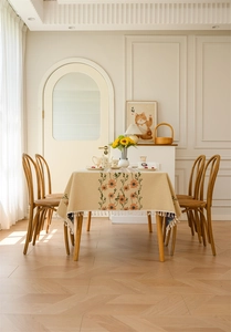 Detail of floral jacquard tablecloth with daisy pattern and white fringe tassels