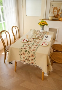 Detail of floral jacquard tablecloth with orange embroidery and white tassel fringe edges