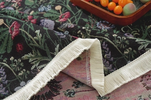 Close-up of floral jacquard fabric texture with elegant white fringe tassel detail