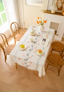 Detail of floral embroidery and elegant tassel trim on cream rectangular tablecloth