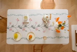 Close-up of floral embroidered linen tablecloth with pink flowers and green leaf patterns