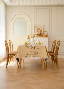 Detail of beige jacquard tablecloth with colorful flower embroidery and white tassels