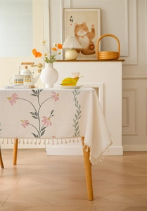 Detail of embroidered floral patterns and tassel edges on white linen tablecloth