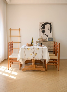 Detailed view of beige waterproof tablecloth with yellow floral embroidery and fringe