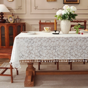 White lace tablecloth with leaf patterns and elegant tassel edges on a rectangular table