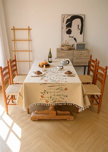 Close-up of floral jacquard pattern and elegant cream fringe edge on a rustic tablecloth