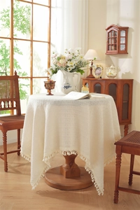 Close-up of beige knit tablecloth with tassel fringe and hollow mesh crochet pattern