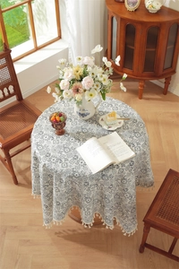 Détail d'une nappe ronde en coton avec imprimé floral et bordure à pompons