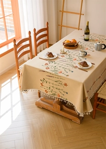 Detail of floral jacquard embroidery on beige tablecloth with tassel fringe edges