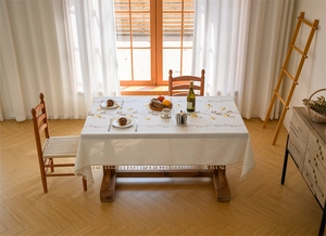 Close-up of embroidered floral patterns and fringe edges on cream rectangular tablecloth