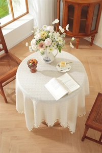 Close-up of beige tablecloth with waffle texture and decorative ball fringe detail