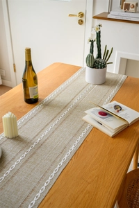 Close-up of hollowed-out table runner with white embroidered chain patterns and tassels