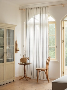 Detail view of white jacquard curtain featuring black chain stripes and elegant fringe edges