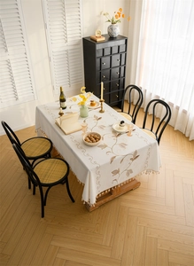Detailed close-up of floral embroidery and pom-pom tassel trim on a linen tablecloth