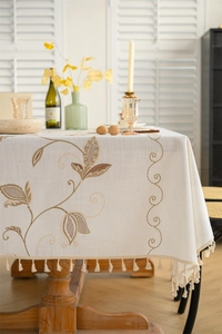 Detail of embroidered floral patterns and tassel edges on rustic linen tablecloth