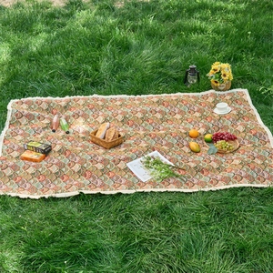 Detail of bohemian outdoor picnic mat with floral jacquard pattern and white fringe edge