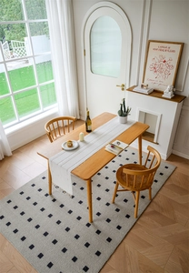Close-up of a white jacquard hollow table runner with handmade tassels on a wooden dining table