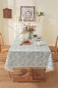 Détail de nappe en coton avec motifs géométriques gris et bordure à pompons blancs