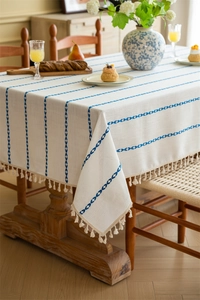 Detailed close-up of bohemian tablecloth fabric texture with blue stripes and tassels
