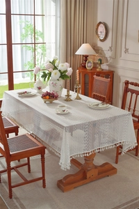 Close-up of white French lace tablecloth featuring hollow stripes and elegant fringe tassels