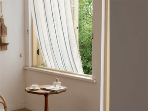 Close-up of jacquard curtains with teal geometric stripes and delicate tassel trim