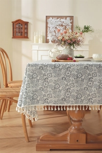 Détail de nappe jacquard bleue et blanche avec pompons en ivoire sur une table en bois