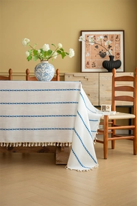 Detail of bohemian ivory tablecloth with blue geometric patterns and fringed tassels