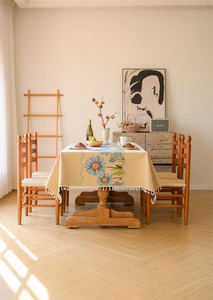 Close-up of beige cotton linen tablecloth with blue floral jacquard and white tassels