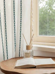 Close-up of white curtains featuring green leaf embroidery and elegant tassel edge detail