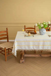 Close-up of bohemian rectangle tablecloth with yellow embroidery and white fringe details