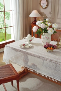 Detail of off-white hollow lace tablecloth with delicate tassels and floral patterns