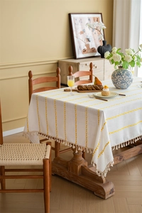 Detail of Nordic white tablecloth with yellow embroidered stripes and fringe