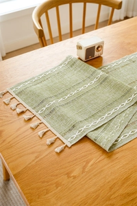 Detail of green woven table runner with hollowed-out lace and white geometric embroidery