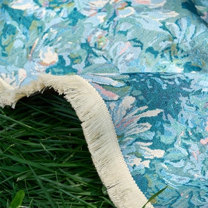 Detailed knit texture of blue floral jacquard tablecloth with creamy white cotton tassels