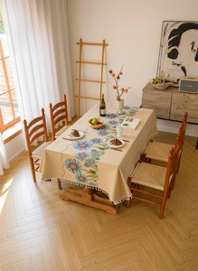 Detail of floral jacquard tablecloth with daisy pattern and white cotton tassels