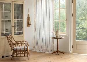 Detail of white polyester jacquard curtain with blue vertical stripes and tassel edges