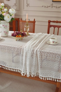 Close-up of white lace tablecloth with hollow patterns and fine fringe tassels