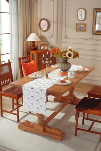 Close-up of a white Halloween table runner with plush ghost embroidery on a wooden table