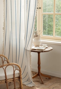 Detail of cream polyester jacquard curtain with blue geometric embroidery and tassels