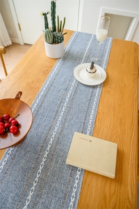 Close-up of blue jacquard table runner with geometric embroidery and white tassels